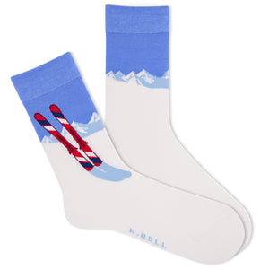 A pair of white women's crew socks with a blue and red graphic design featuring skis and a mountain range. The brand name 'K.Bell.'