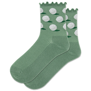 A pair of green crew socks with a lettuce edge design and white golf ball patterns, displayed on a piece of grass next to a golf club and two golf balls.