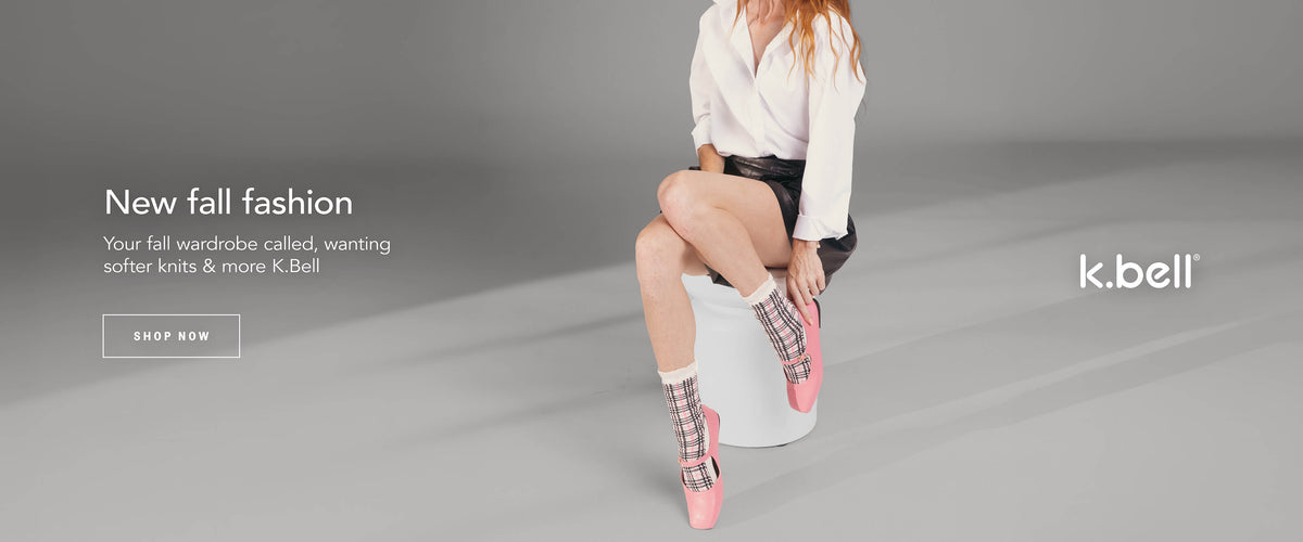 A person wearing pink-and-black plaid crew socks with a ruffled top trim, set against a light gray studio background with promotional text for K.bell.