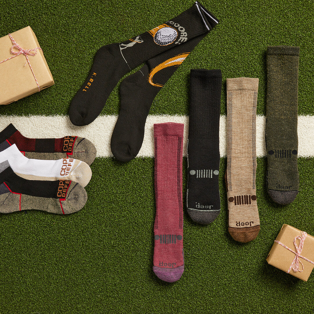 Collection of socks with brand name on a grass-like surface with small gift boxes.
