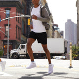 Person in athletic wear crossing a city street with urban buildings in the background