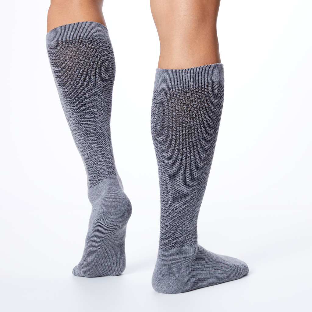 Back profile of a man wearing a pair of gray over the calf compression Dr. Scholl's socks.