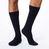 Side profile of a man wearing black, knee high Dr. Scholl's compression socks.