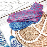 Stack of colorful knitted socks on a woven mat with beads thumbnail