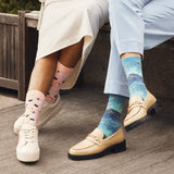 Two women sitting on a bench wearing HOTSOX novelty socks. thumbnail