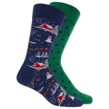 A pair of crew socks shown overlapping on a white background. The front sock is navy blue with a winter village pattern featuring red cabins, snow, trees, and orange sleighs. thumbnail