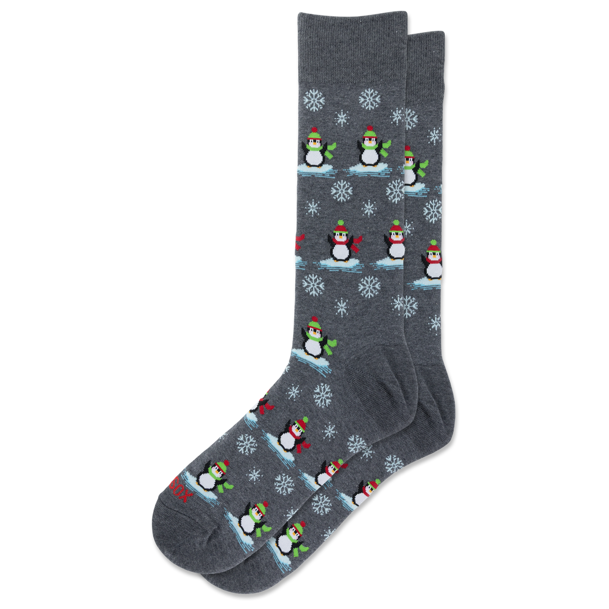 A pair of dark gray crew socks featuring a repeating pattern of penguins wearing red and green hats and scarves, standing on icy blue platforms with white snowflakes.
