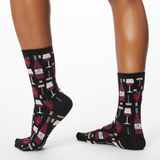 Woman wearing black socks with wine-themed pattern on a white background