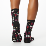 Woman wearing black socks with wine-themed pattern on a white background