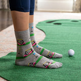 Person wearing gray socks with golf cart design on a putting green
