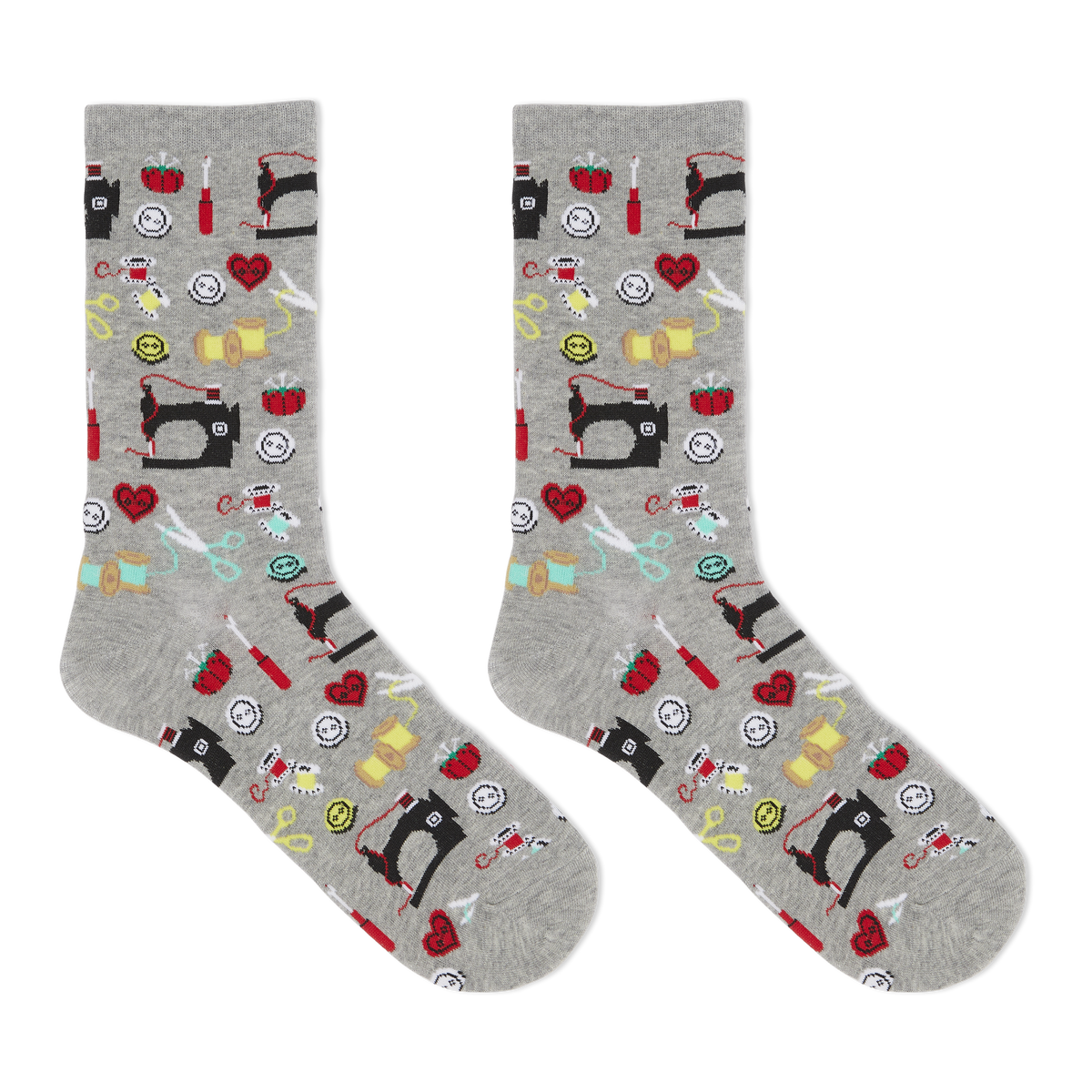 A pair of heather gray crew socks with an all-over sewing-themed pattern featuring black sewing machines, red hearts, yellow spools, scissors, and other colorful thread icons, shown against a plain white background.