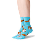 A pair of light blue crew socks with a repeating pattern of brown and white cat illustrations, shown on a person's feet against a white background.