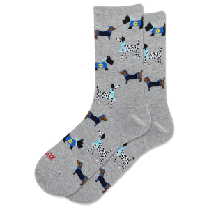 A pair of heather gray crew socks featuring an all-over pattern of various dogs in navy blue and black Hanukkah-inspired outfits, with one sock showing the red text 'HOTSOX' near the toe.