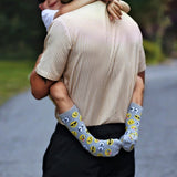 Child wearing socks with emoji patterns, embracing his father outdoors.