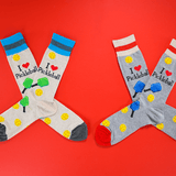 Two pairs of pickleball-themed socks on a red background