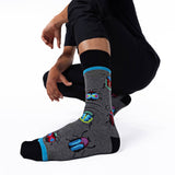 Person wearing gray socks with colorful beetle designs on a white background