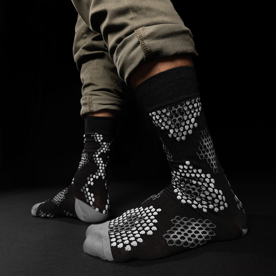 Black socks with white pattern worn by a person on a black background