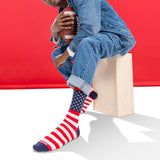 Person wearing American flag socks sitting on a box against a red background