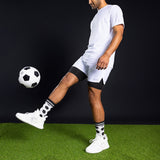 Person in white sports outfit kicking a soccer ball on a green field with black background