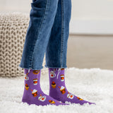Purple socks with coffee-themed design worn with blue jeans on a white carpet.