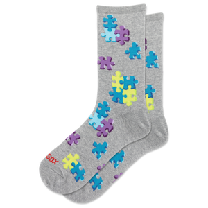A pair of heather gray crew socks with a pattern of colorful puzzle pieces in blue, purple, and yellow. The brand name 'HOTSOX' is printed in red on the toe area.