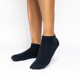A pair of low-cut black socks worn on a person's feet, shown against a plain white studio background.