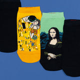 Three novelty ankle socks displayed on a blue background, featuring artwork from Gustav Klimt's 'The Kiss' and Leonardo da Vinci's 'The Mona Lisa' on black socks. thumbnail