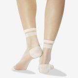 A pair of sheer nude ankle socks worn on a model's feet, shown from the back against a clean white background.