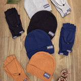 Collection of Jeep-branded beanies and gloves on a wooden surface with pine cones. thumbnail