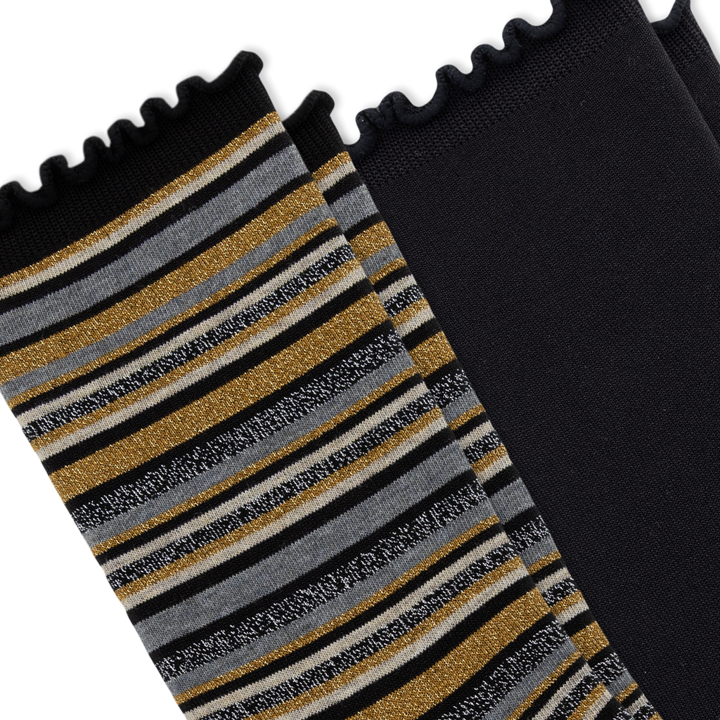 A close-up of a pair of black socks with one sock featuring horizontal stripes in black, gray, white, and shimmering gold, and the other sock is solid black, set against a plain white background.