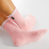 Pink socks with white stripes worn by a person on a light gray background