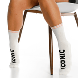 White socks with 'Iconic' branding worn by a person sitting on a chair. thumbnail
