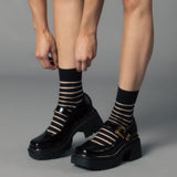 Black platform shoes with striped socks on a gray background