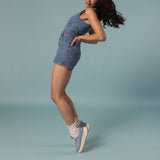 Woman wearing a denim outfit with sneakers and white slouch socks on a light blue background thumbnail