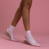 Person wearing pink slipper shoes and socks with a pink background thumbnail