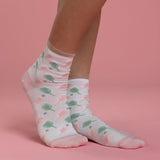 White socks with green and pink pickleball patterns worn by a person on a pink background thumbnail