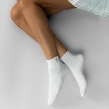 Person wearing light blue socks with a small embroidered golf ball on a light gray background thumbnail