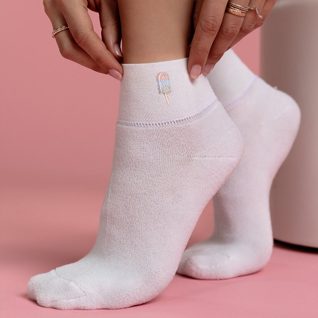White socks with a small embroidered popsicle on a pink background
