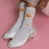 White socks with heart and chain design worn with white shoes on a pink background