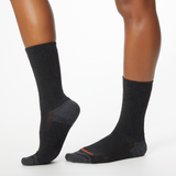 Side profile of a woman wearing black MERRELL socks with orange and gray accents at the heel and toe