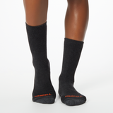 Front profile of a woman wearing black MERRELL socks with orange and gray accents at the heel and toe