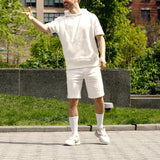 Person wearing a white outfit standing outdoors with greenery in the background