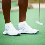 White golf shoes with yellow socks on a green putting surface thumbnail
