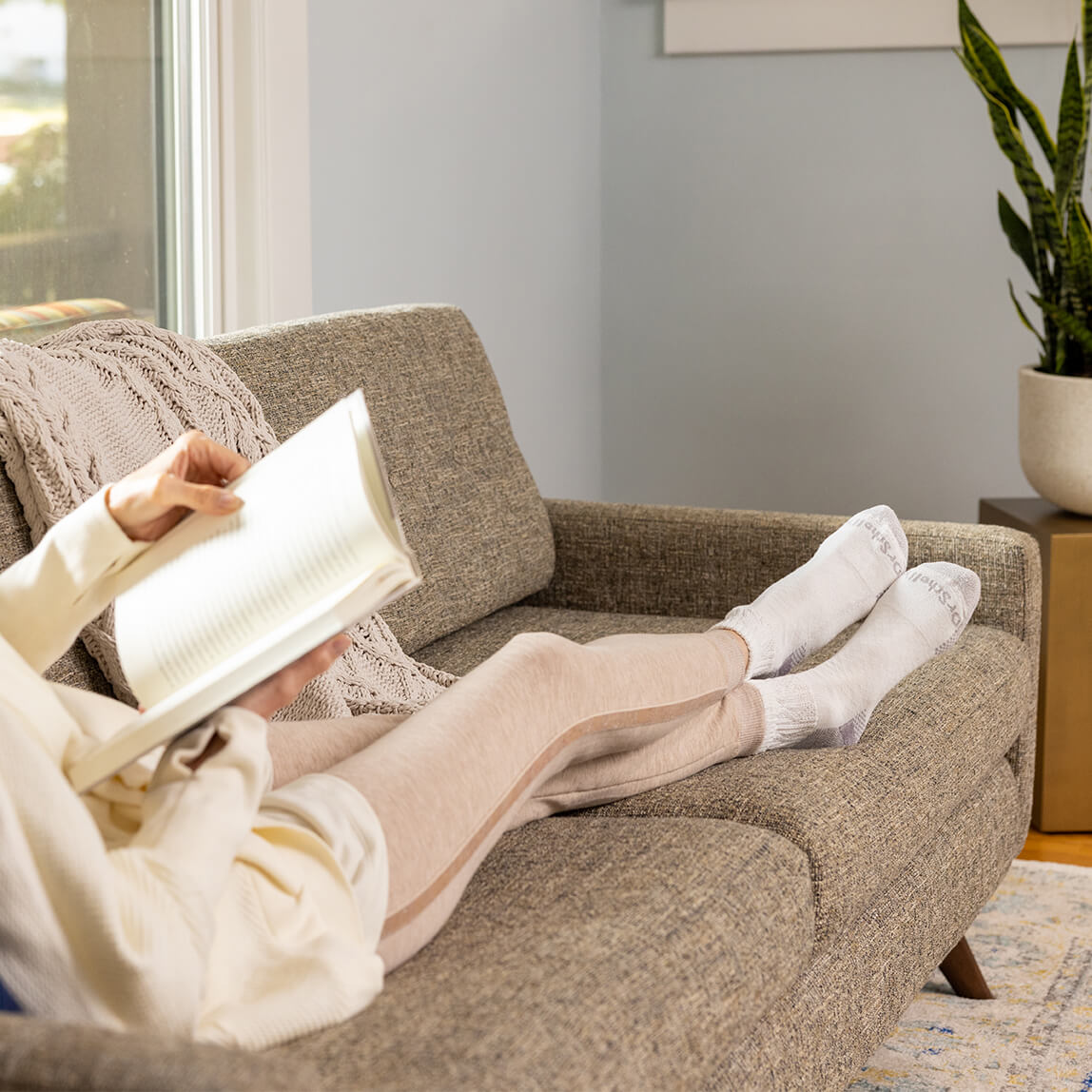 Person reading a book on a couch in a cozy living room.