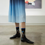 Person wearing socks with a design of a woman with a pearl earring in an indoor setting. thumbnail
