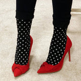 Red high-heeled shoes with black polka dot socks on a neutral background