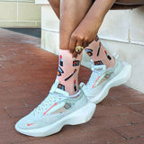 Person wearing light blue sneakers with transparent panels on a brick pavement.