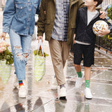 Three people walking on a wet street, with one person holding a soccer ball. thumbnail