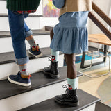 Two children standing on a staircase wearing colorful socks with cartoon characters. thumbnail