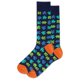 Navy sock with green and blue puzzle piece pattern and orange toes and heels on a white background